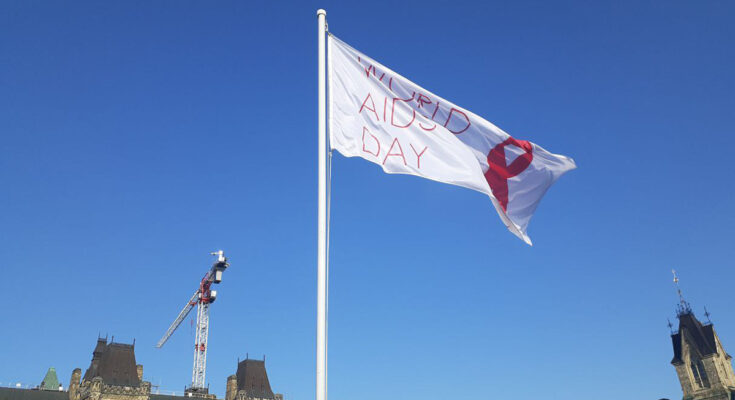 A Flag with World AIDS Day written on it flies against the blue sky