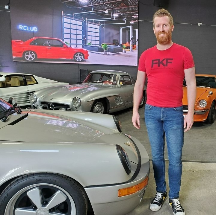 man in red T-shirt with classic sports cars
