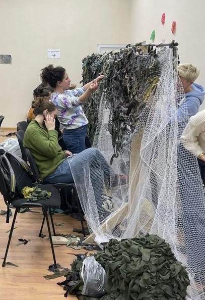 women tying green rags to netting
