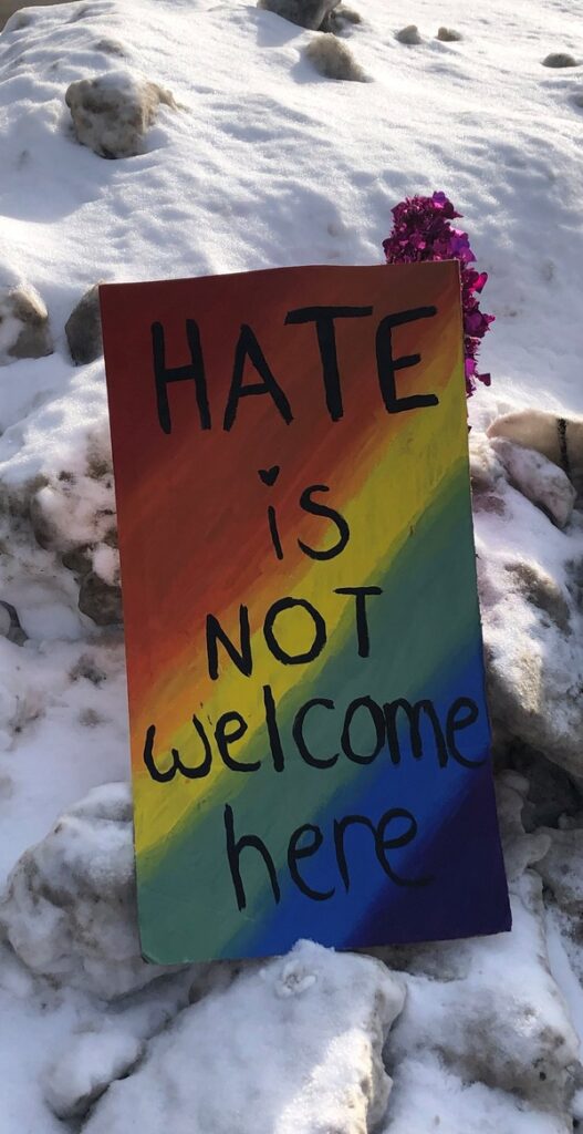 Rainbow sign in snowbank saying "Hate is not welcome here"