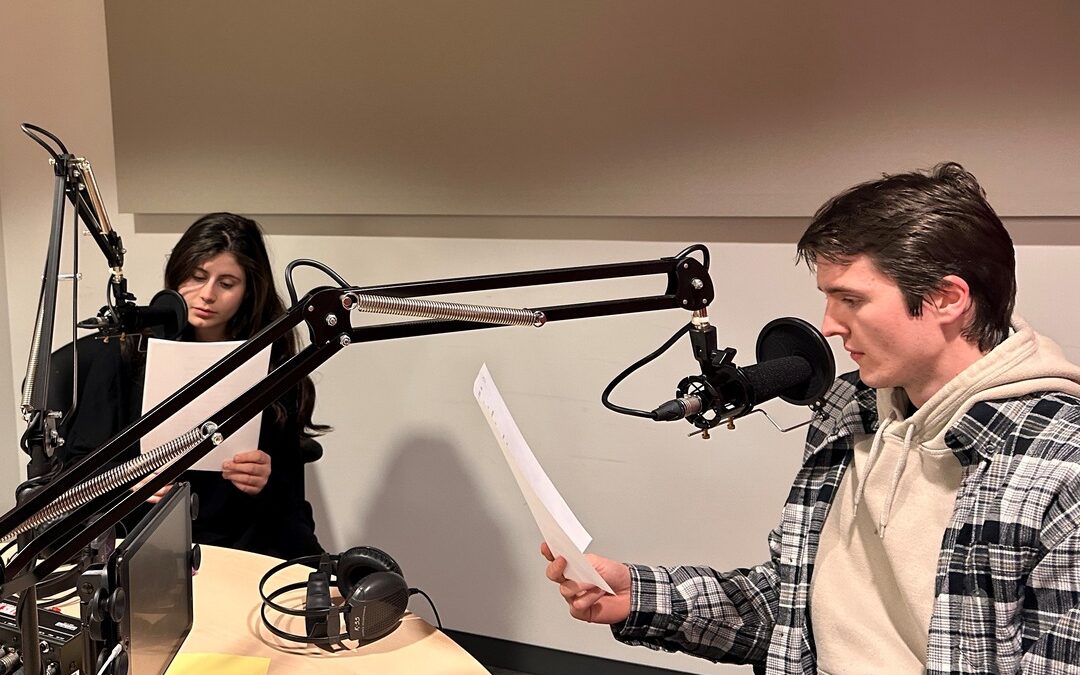 two hosts at the microphones in studio