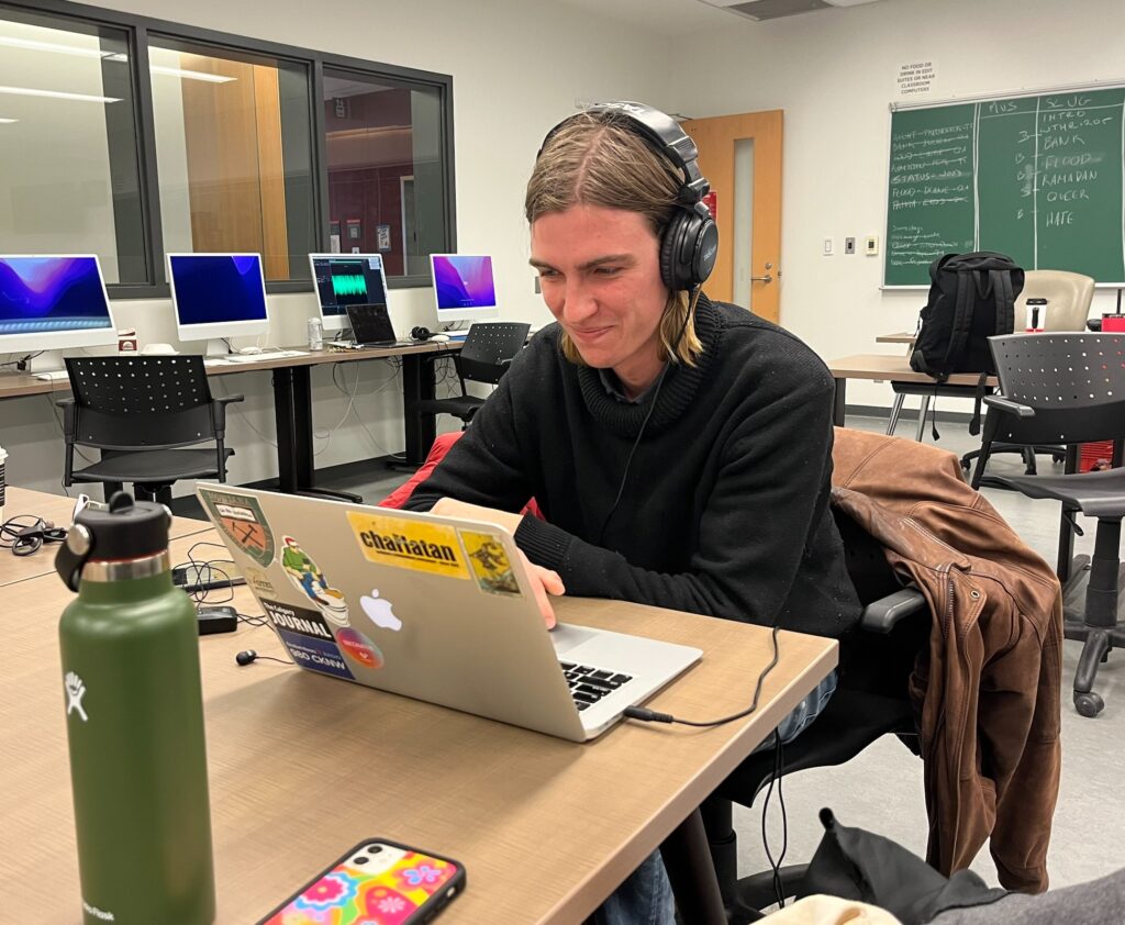 smiling reporter working at computere, wearing headphones