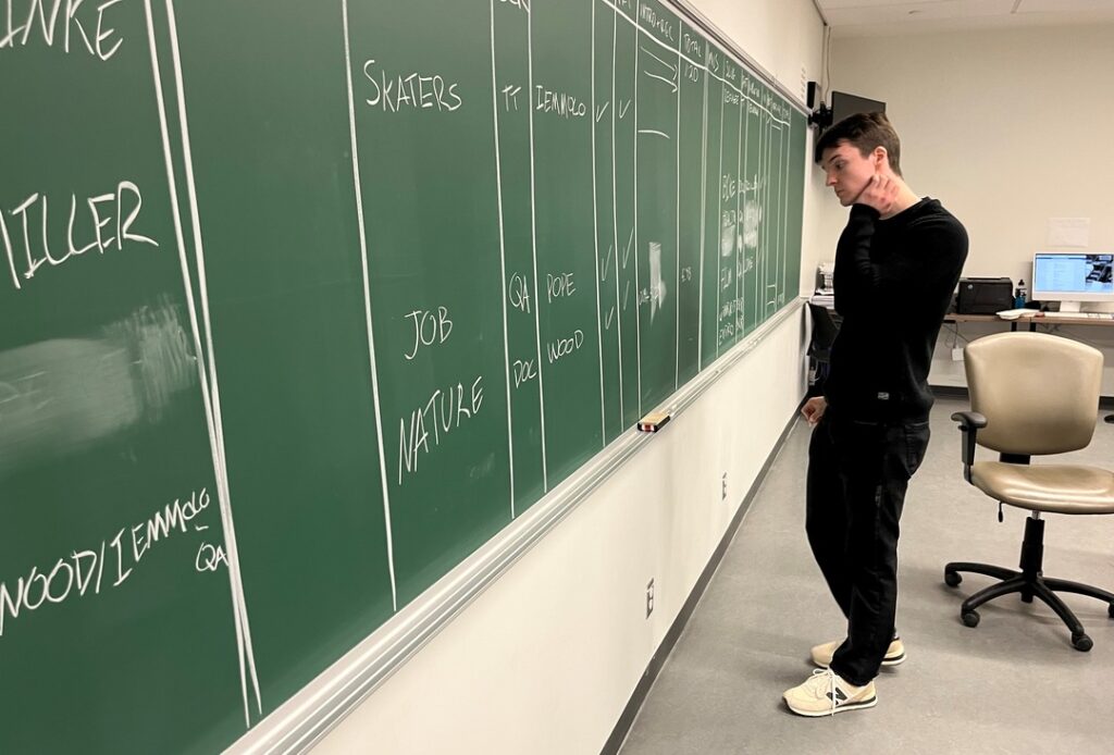 A lonely producer stands at the chalkboard, pondering the line up. 