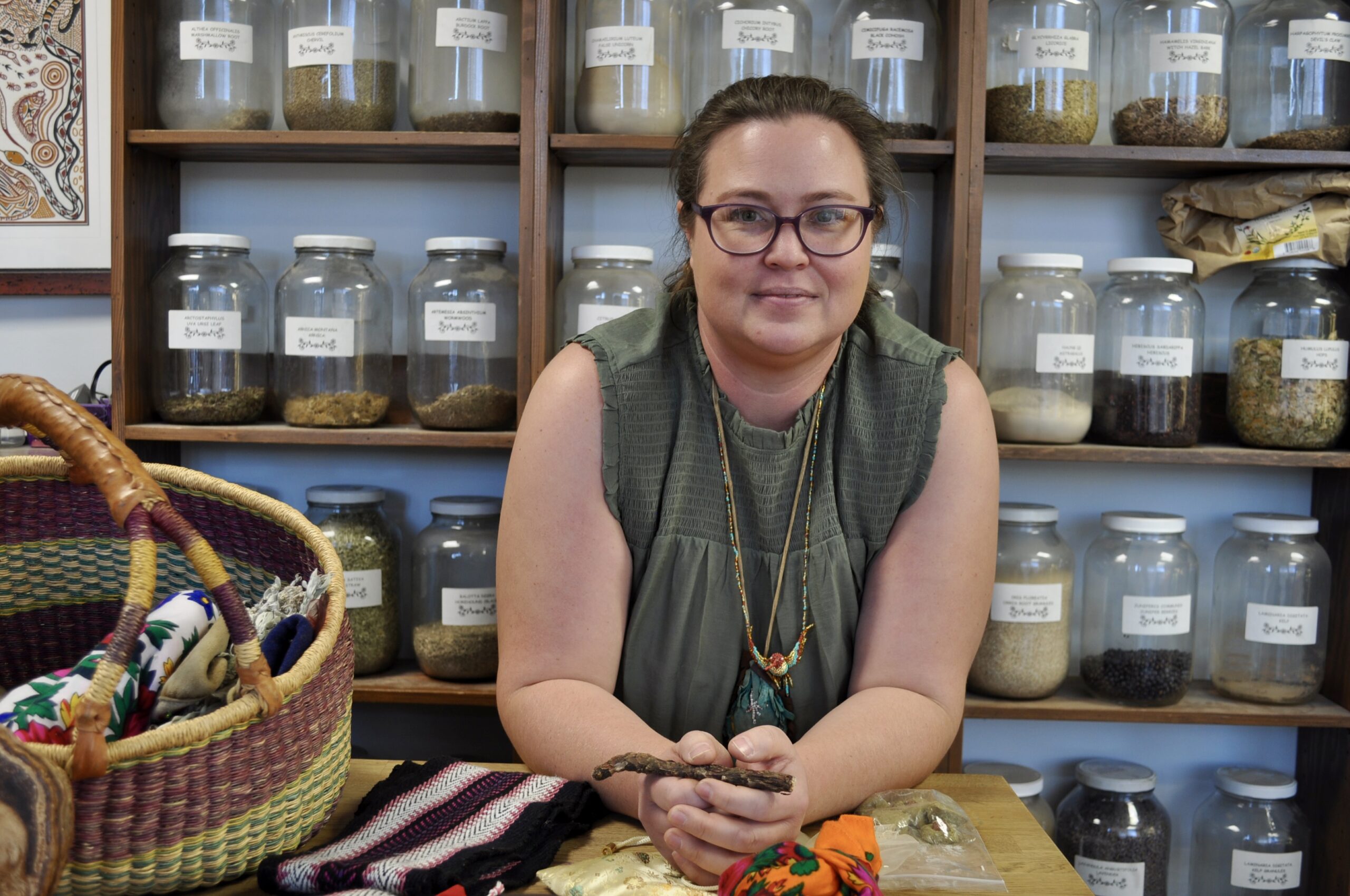 Kalyn Kodiak stands in front of wall filled with herbs and natural medicines.