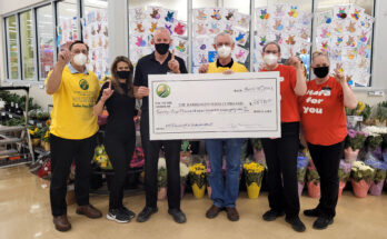 Six individuals hold a large cheque made out to the Barrhaven Food Cupboard while holding up one finger.