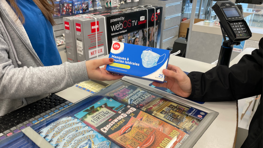 A cashier handing masks to a customer.