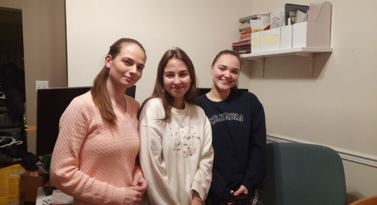 Three women stand together.