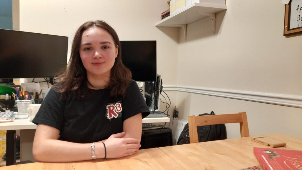 A woman in black T-shirt sits at the table smiling.