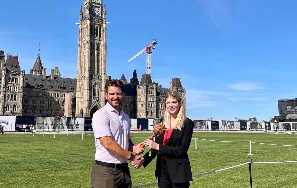 Former Ukrainian Canadian Students’ Union president Roman Grod, passes the ceremonial mace, known as a buvala in Ukrainian, to the new president, Danya Pankiw, on Sept. 27, 2021. Photo provided by Danya Wasylyk.