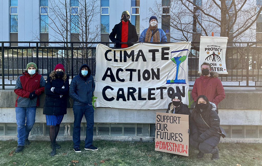 Student activists stand in front of a banner that reads Climate Action Carleton.